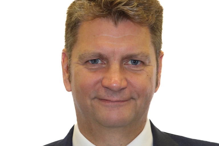 A corporate headshot of a man in a suit