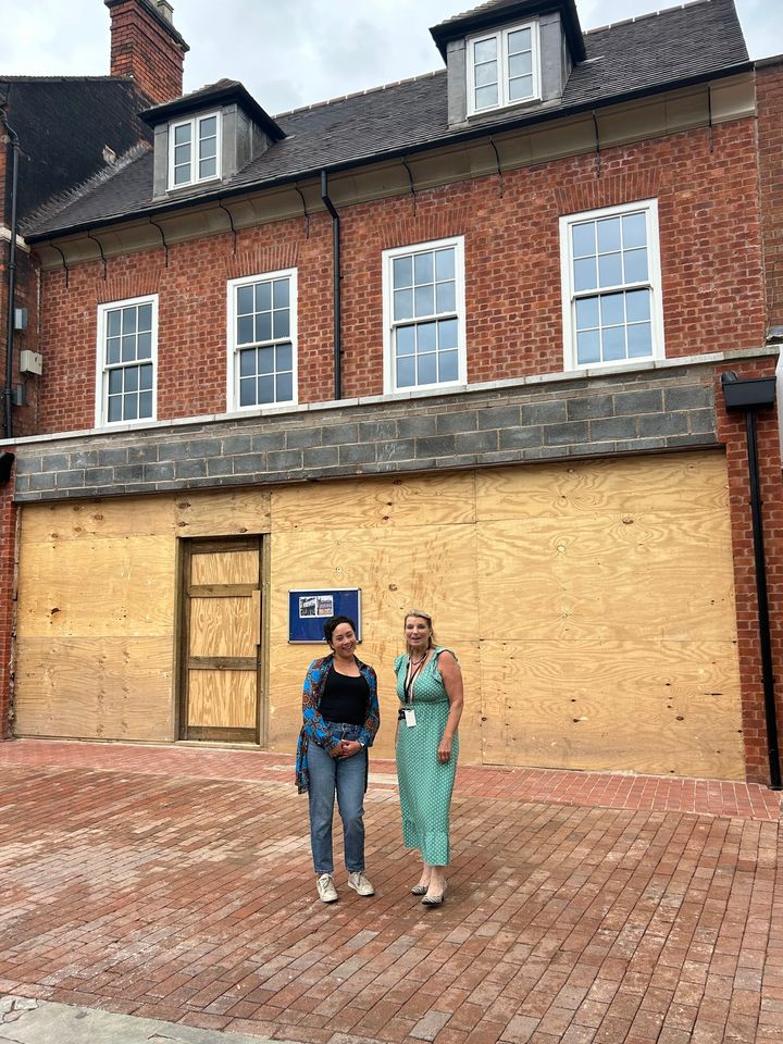 Photo of Cllr Dean and Cllr Arkney outside the former Peel cafe. Wooden hoarding is outside the front of the building