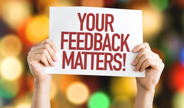 Hands holding up a sign saying 'your feedback matters!'
