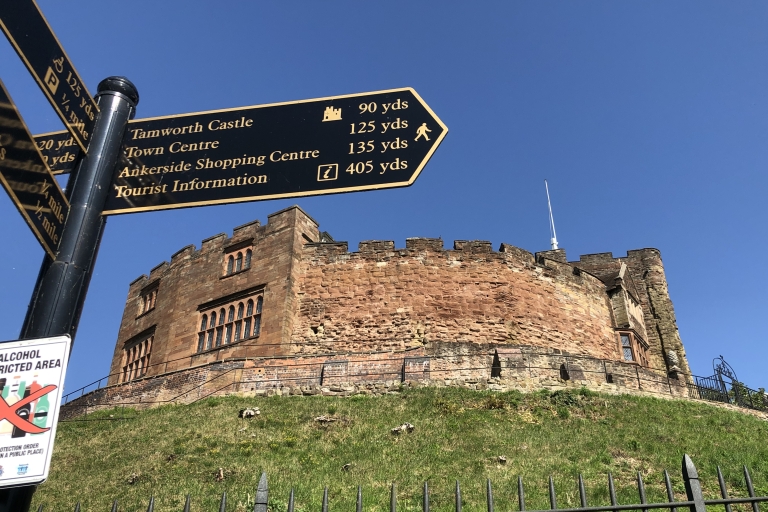 Tamworth Castle on a grassy hill. A signpost is in front of it.