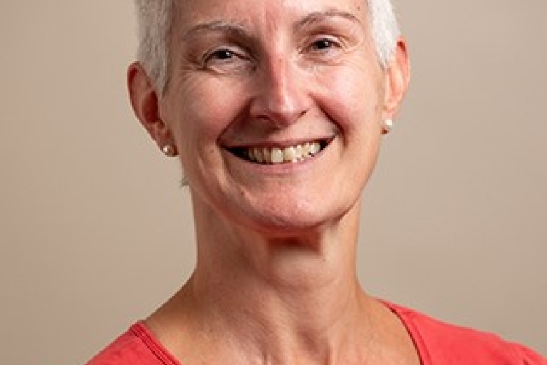 photo of a person with light short hair wearing an orange top