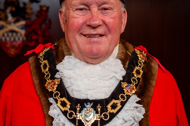 male wearing mayor red robes and hat, gold chains 