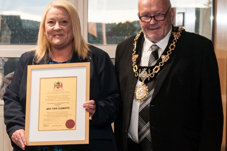 photo of a lady and mayor holding a framed certificate