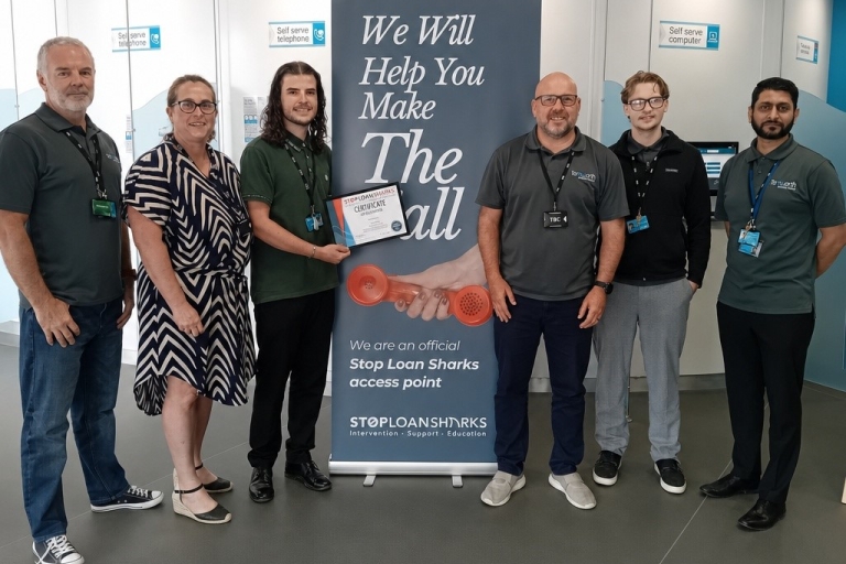 group of people standing by a poster, holding a certificate
