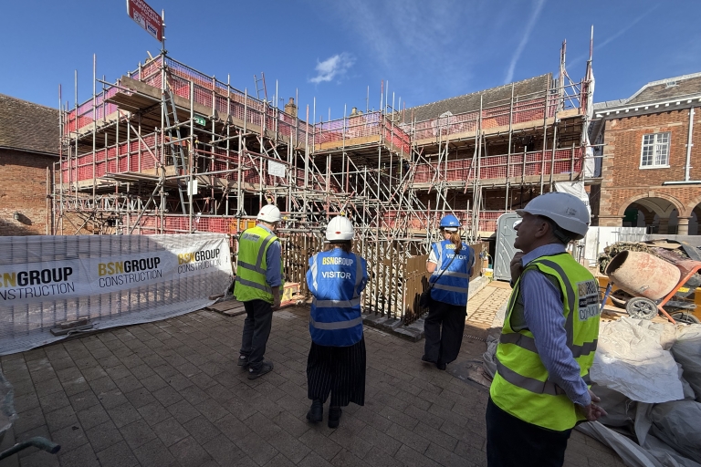 4 people in front of Market St properties in Tamworth with high vis and hard hats as the building is getting restored and has lots of complex scaffolding up around it.