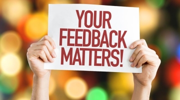 Hands holding up a sign saying 'your feedback matters!'