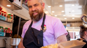 Photo of Ben Newman aka spudman holding a jacket potato in a container inside his spud van