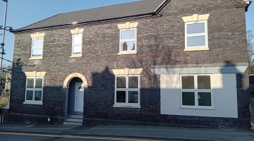 image of the front of a large grey brick home 