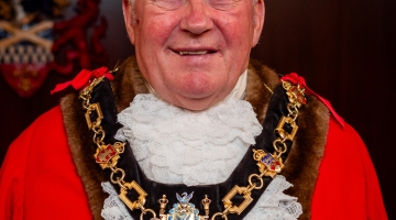 male wearing mayor red robes and hat, gold chains 